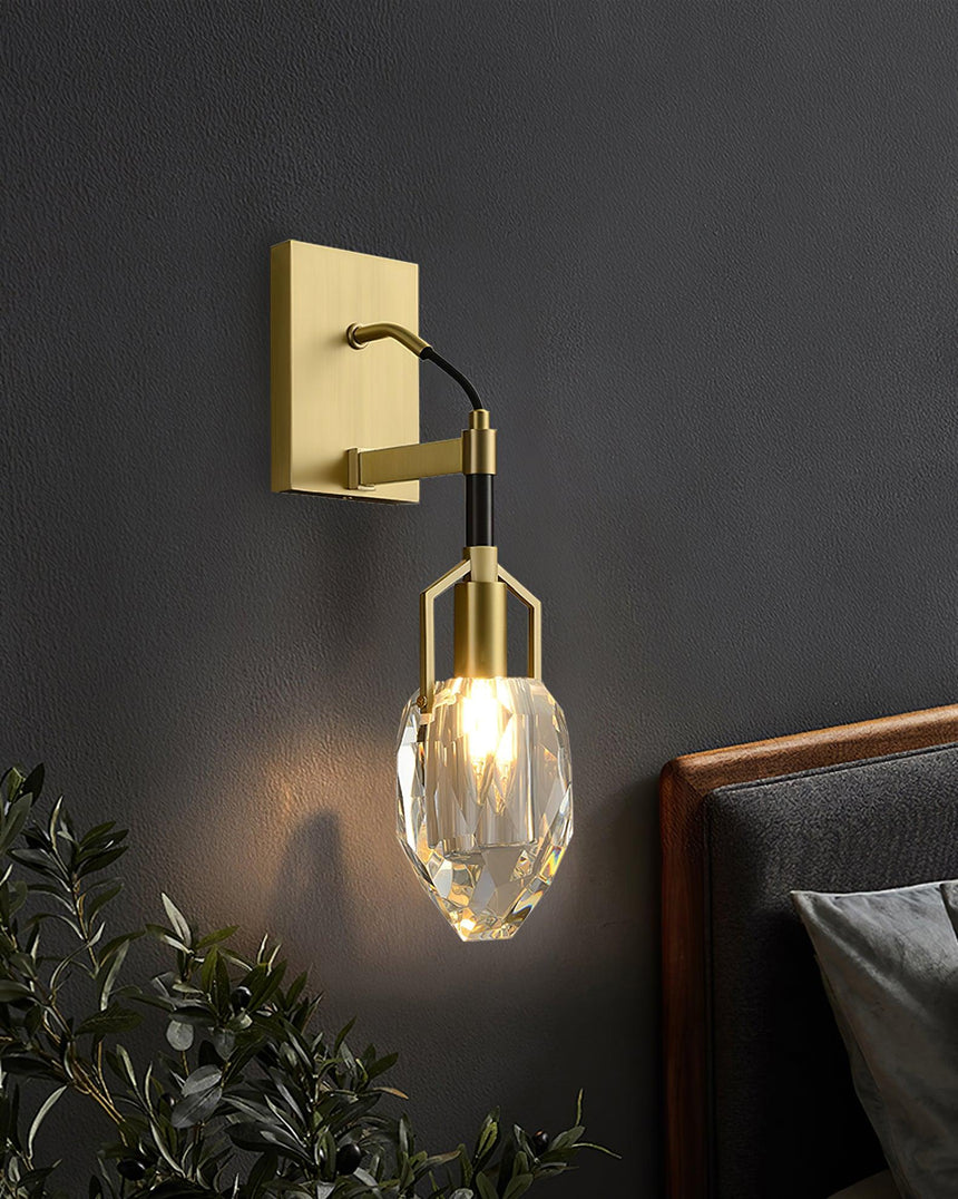 The crystal drop lit beside a dark headboard above a plant