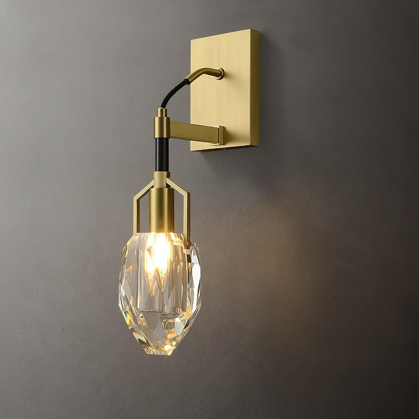 The crystal drop lit warm on a gray wall, the facets glowing
