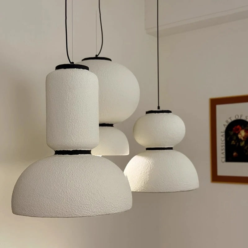 Three textured pendants of different heights in a pale room
