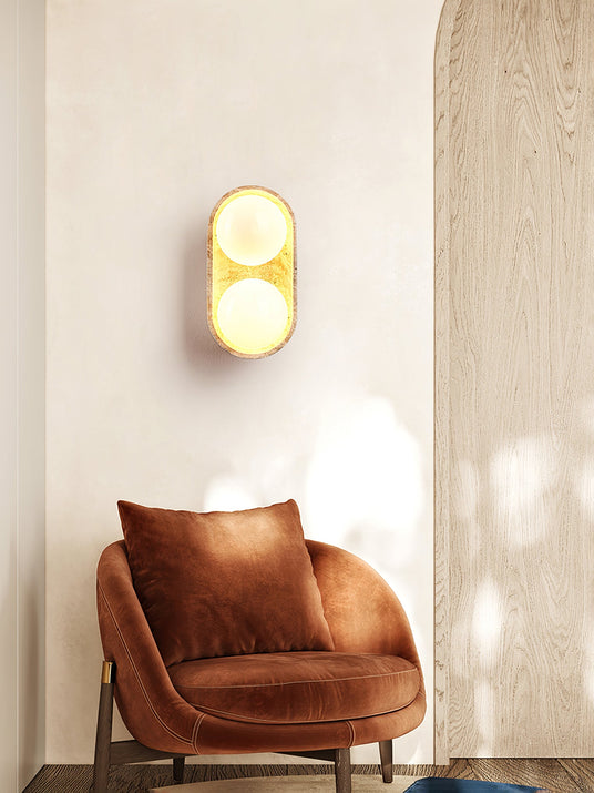 Sconce lit above a rust velvet armchair beside a wood panel and a cushion