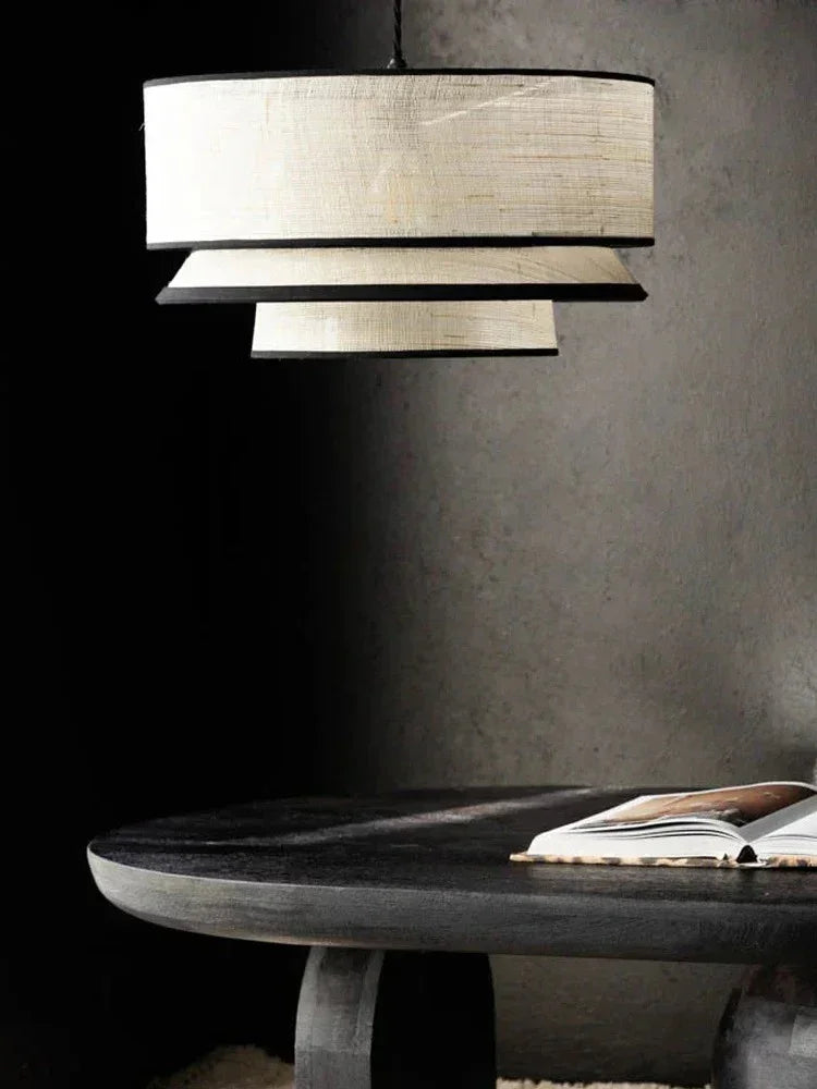 Tiered drum pendant light above a dark dining table