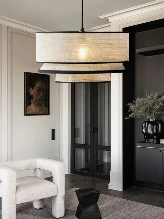 Tiered drum pendant light lit in a living room with an armchair