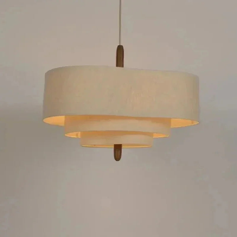 Two tier drum shade lit warm against a plain wall