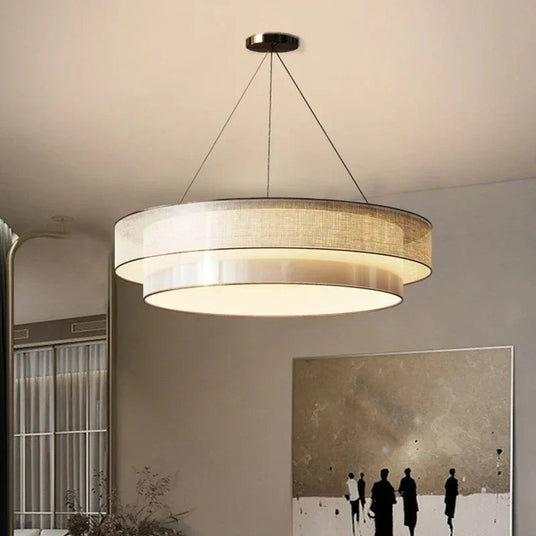 Tiered drum pendant light lit in a tall living room beside framed artwork