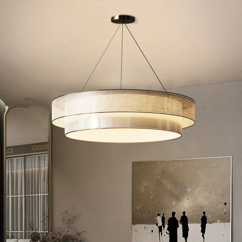 Tiered drum pendant light lit in a tall living room beside framed artwork