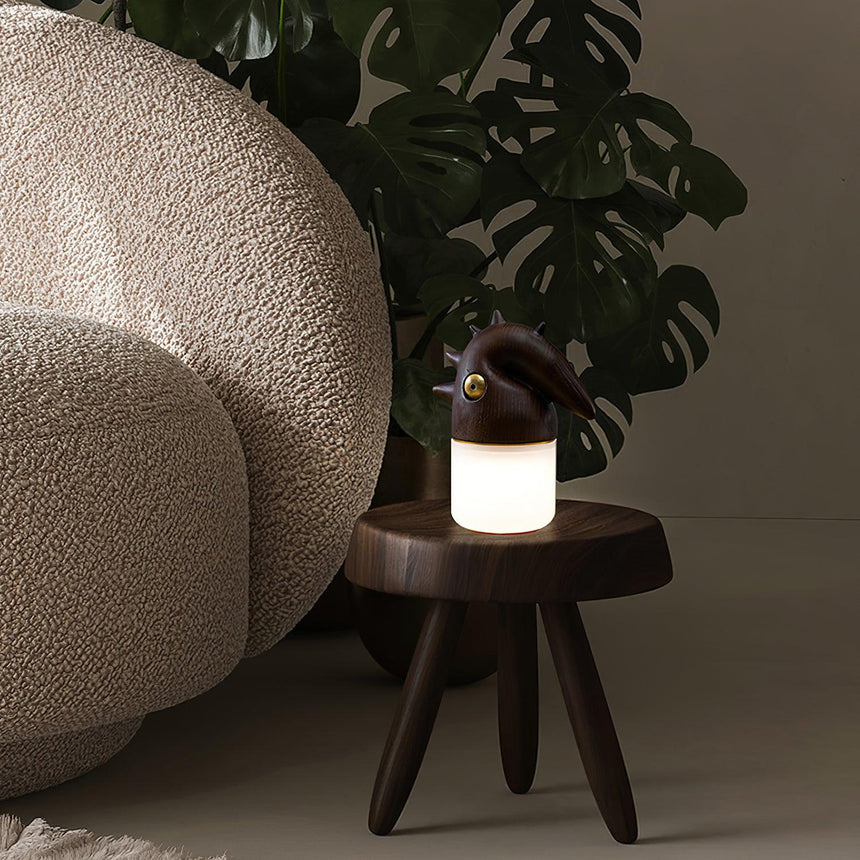 Touch control bedside lamp lit on a stool beside a large plant