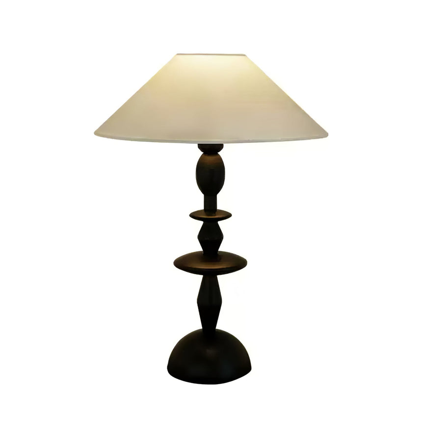 Turned spindle table lamp in black against a plain white ground