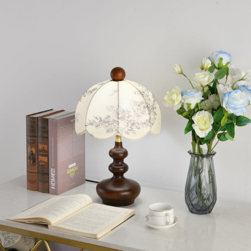 Toile shade lamp lit brightly beside roses and bound books