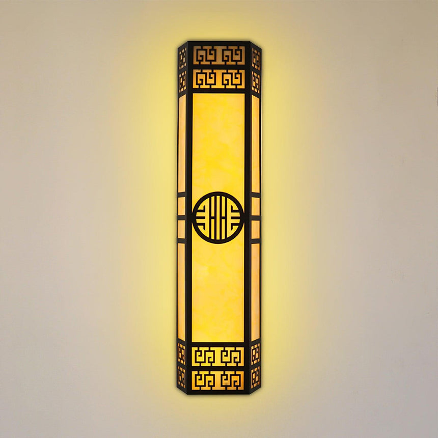 The column lit warm on a beige wall, the fretwork dark against the glowing panels