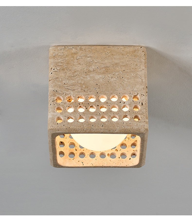 Underside of the square travertine block ceiling light with a lit diffuser