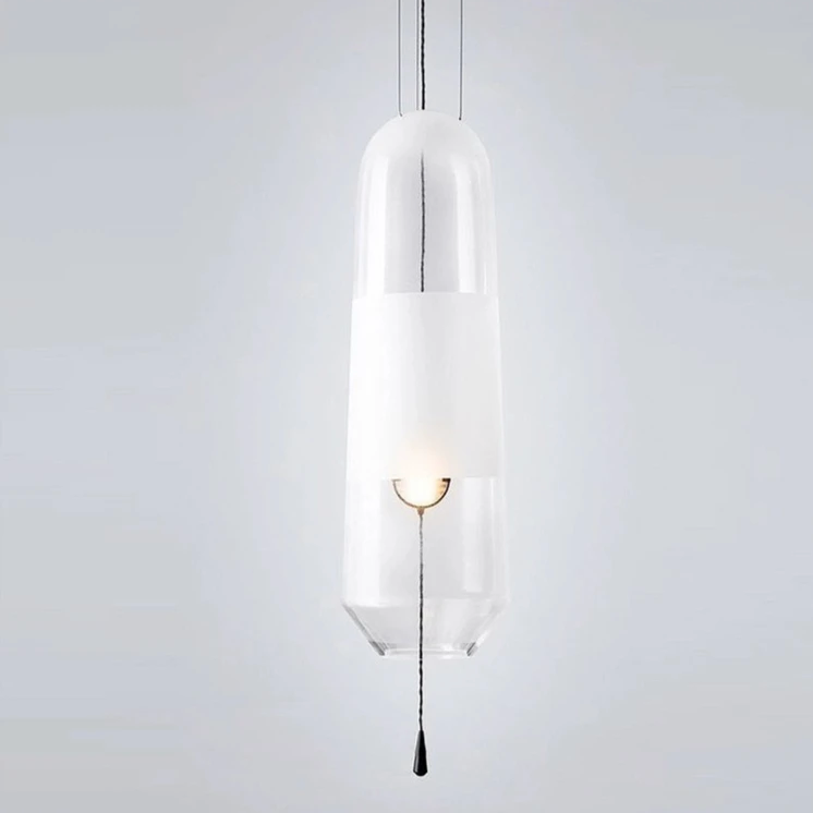 A clear glass tube pendant lit with its white inner cylinder showing
