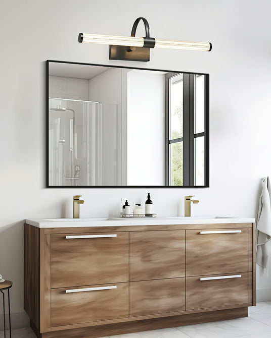 Dark arch and tube lit above a framed mirror over a walnut double vanity