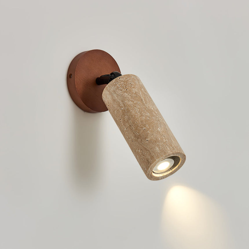 Travertine tube tilted down on its walnut base, throwing a spot on the wall