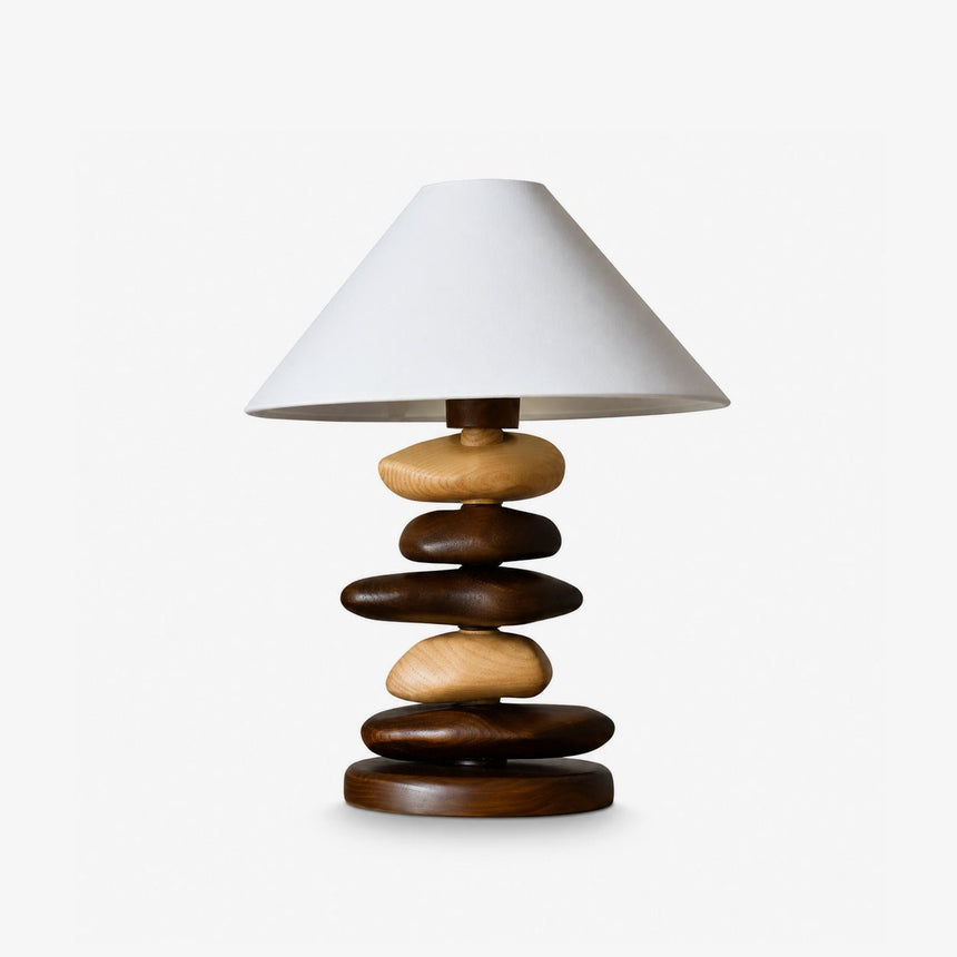 Unique table lamp with stacked wood pebbles under a cream cone shade