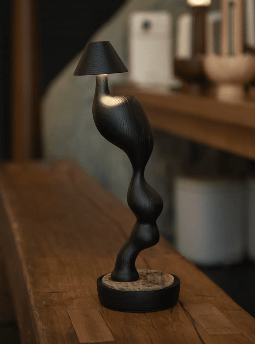 Matte black cordless table lamp on a wooden bench in a kitchen