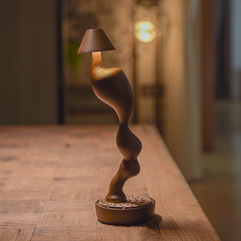 Cordless carved wood table lamp lit on a wooden surface at night