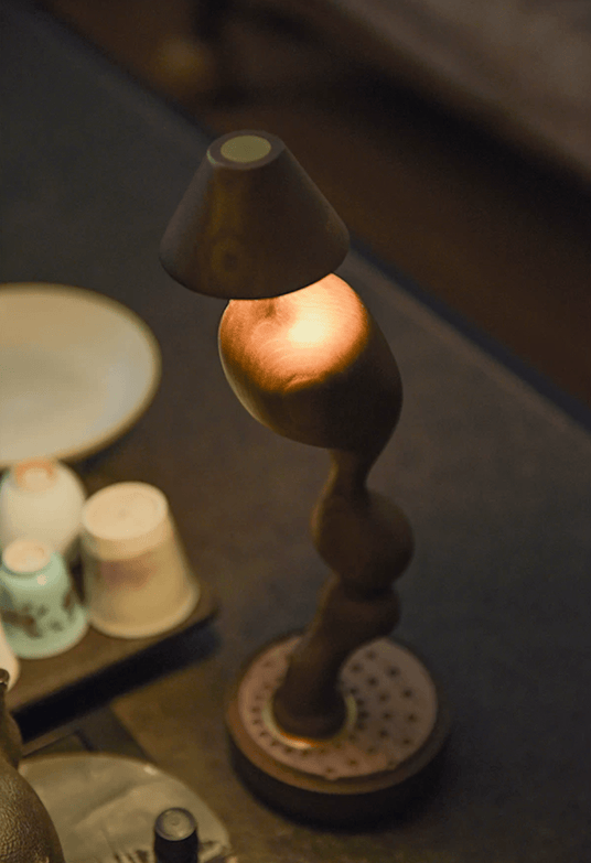 A finger touching the cone shade to change the brightness of the lamp