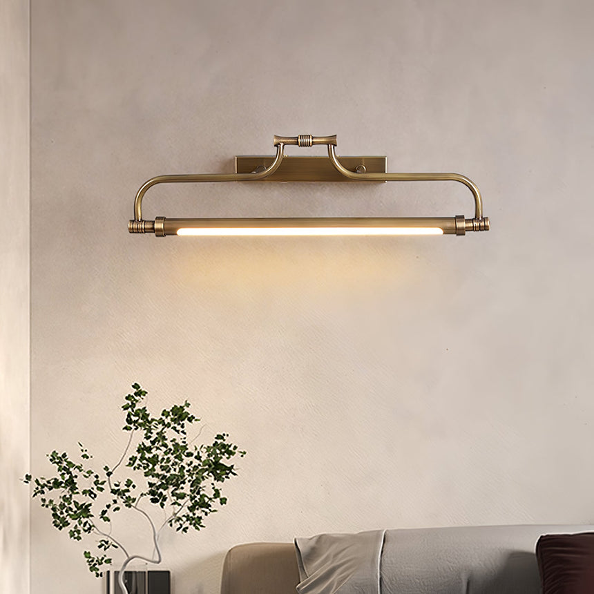 Bracket lit on a plaster wall above a plant and a low couch in a warm room