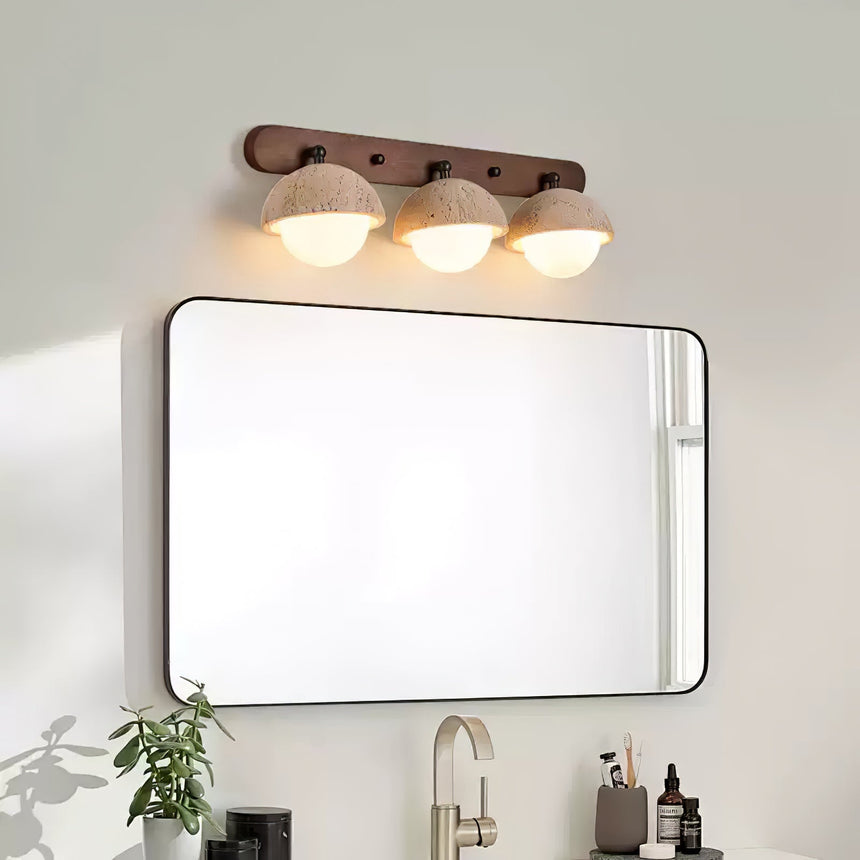 Three domes lit above a framed mirror and a basin with bottles below