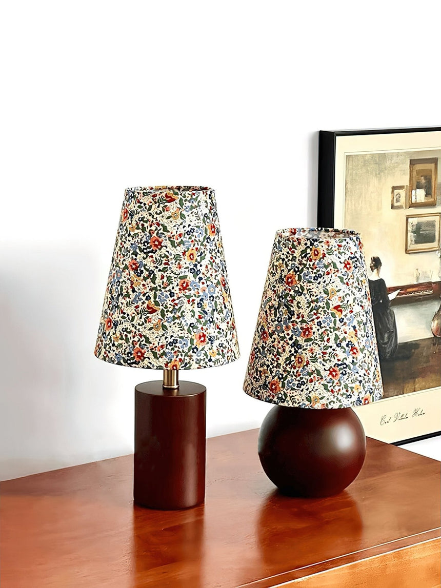Two floral shade lamps lit together on a wood sideboard