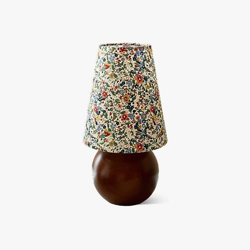 Floral shade lamp on a wood sphere base against a plain ground