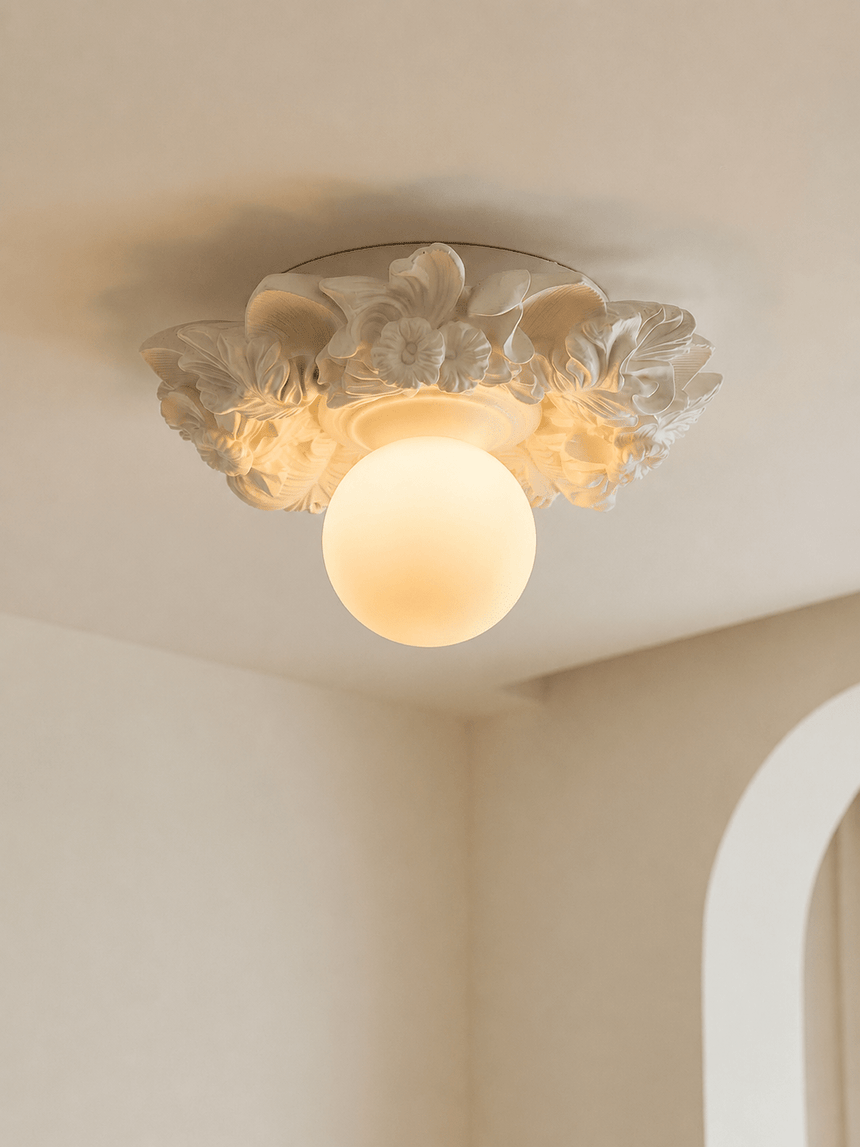 Carved floral ceiling light lit against a pale ceiling at an angle
