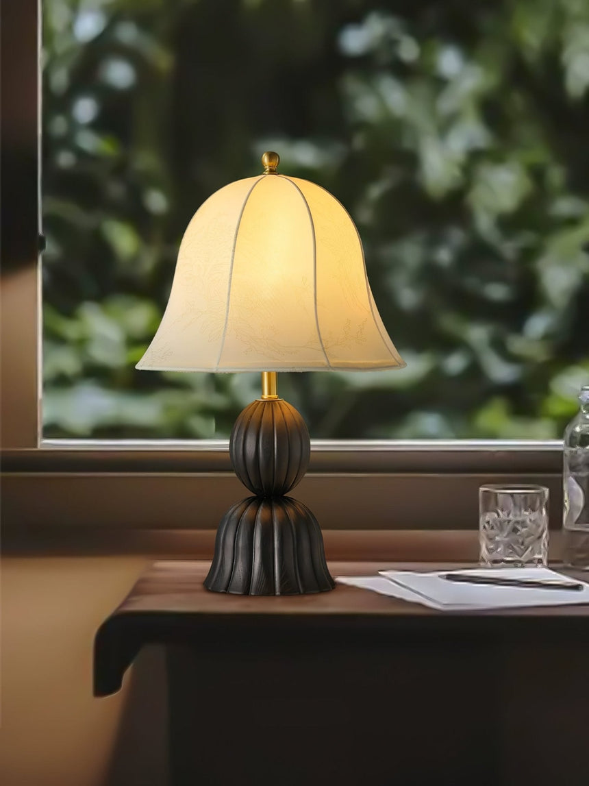 Black based vintage table lamp on a table in front of a garden window
