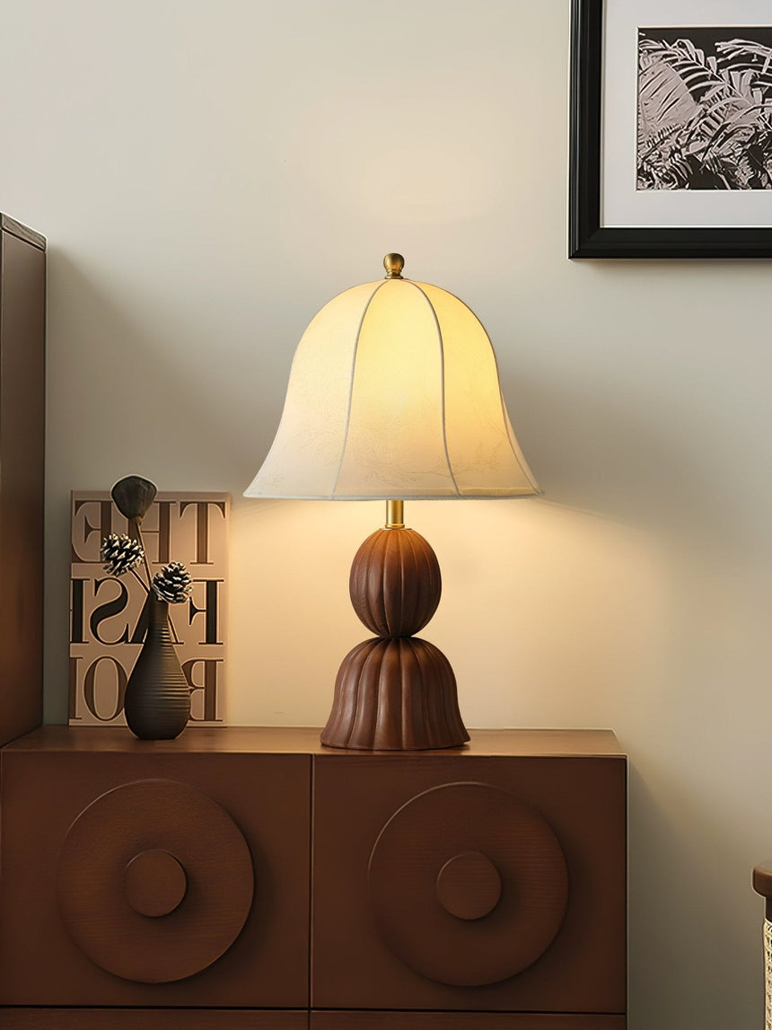 Vintage table lamp lit on a wooden cabinet beside a framed print