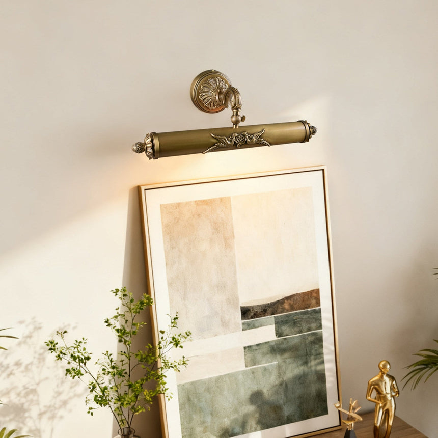 Scrolled brass bar lit over a framed canvas beside trailing green branches