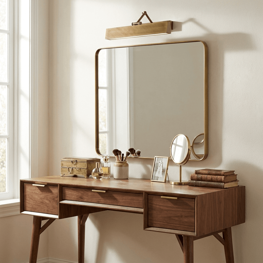 Bronze bar lit above a mirror on a walnut dressing table with brushes and books