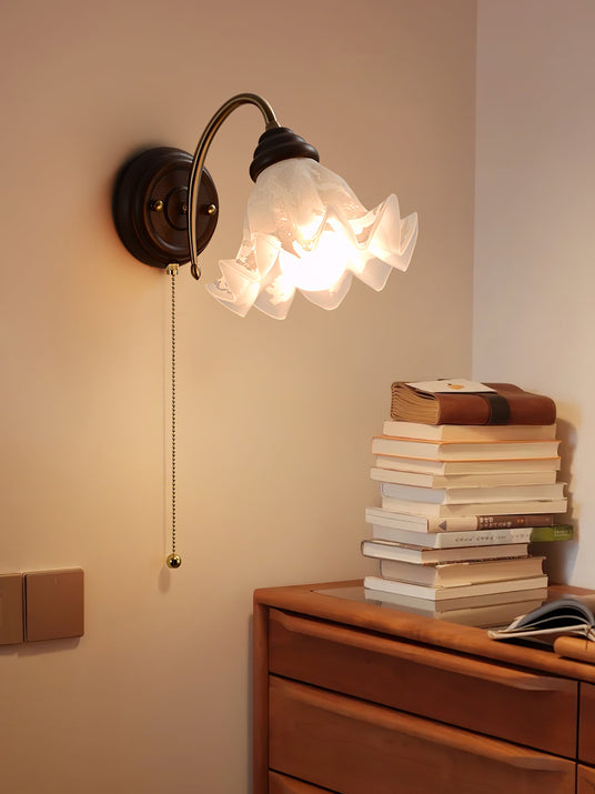 Sconce lit above a wood chest holding a tall stack of worn books