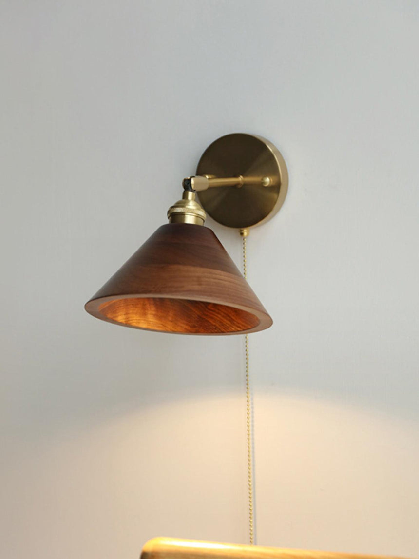 Walnut cone sconce lit and seen at an angle on a plain wall