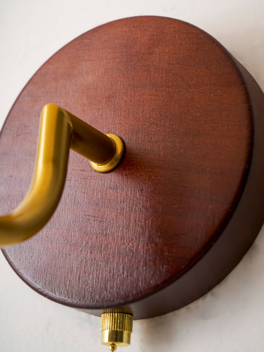 Detail of the round dark wood backplate and the brass arm joint