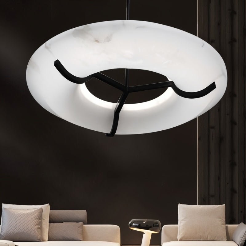 The lit ring in a dark living room above two pale sofas and a low table