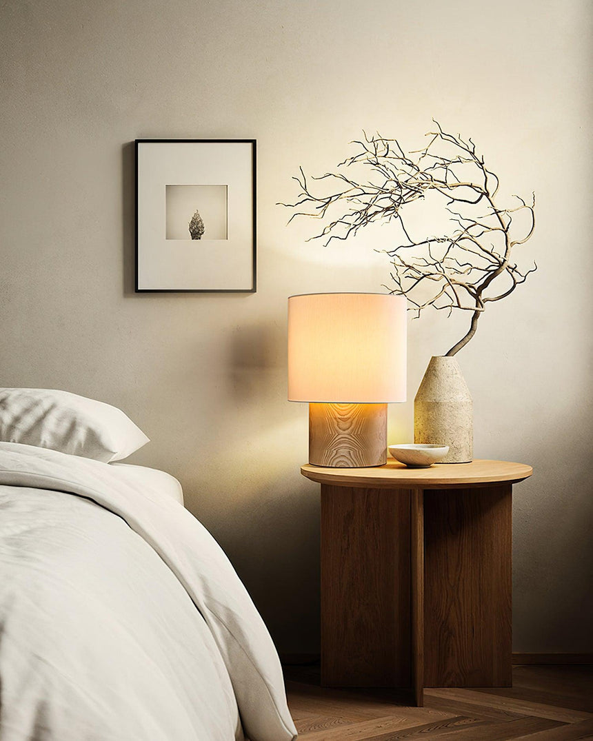 Wabi sabi table lamp lit beside a bed with dried branches