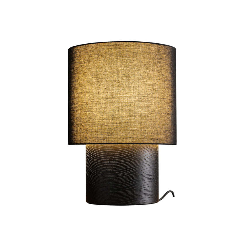 Wabi sabi table lamp with a black shade lit on a plain ground