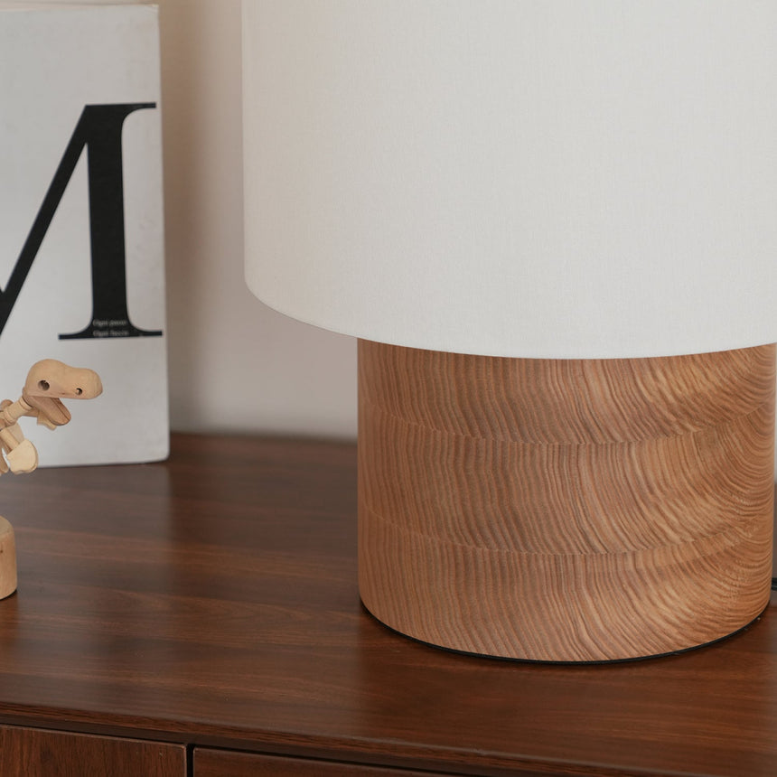 Wabi sabi table lamp lit on a walnut sideboard beside a book