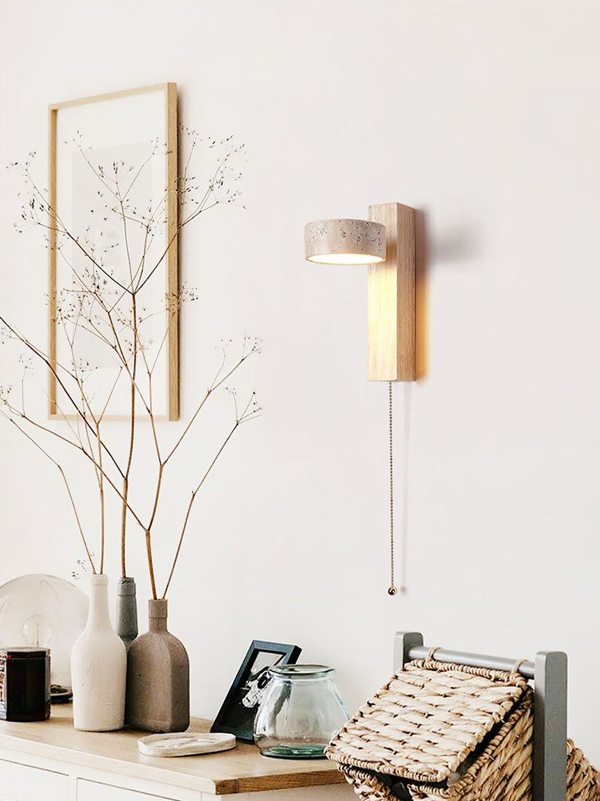 Lamp lit above a shelf of pale vases, framed prints and a woven basket