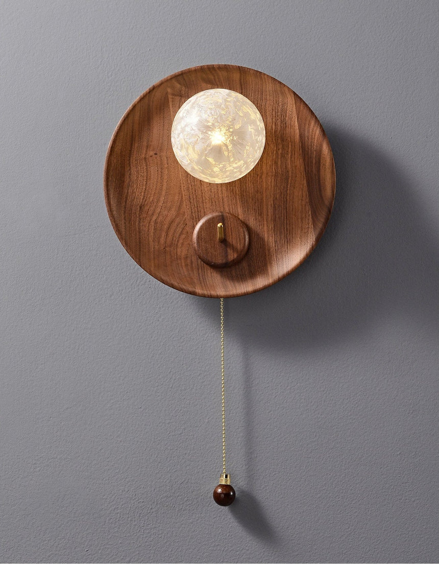 The walnut disc unlit, the textured globe pale against the grain