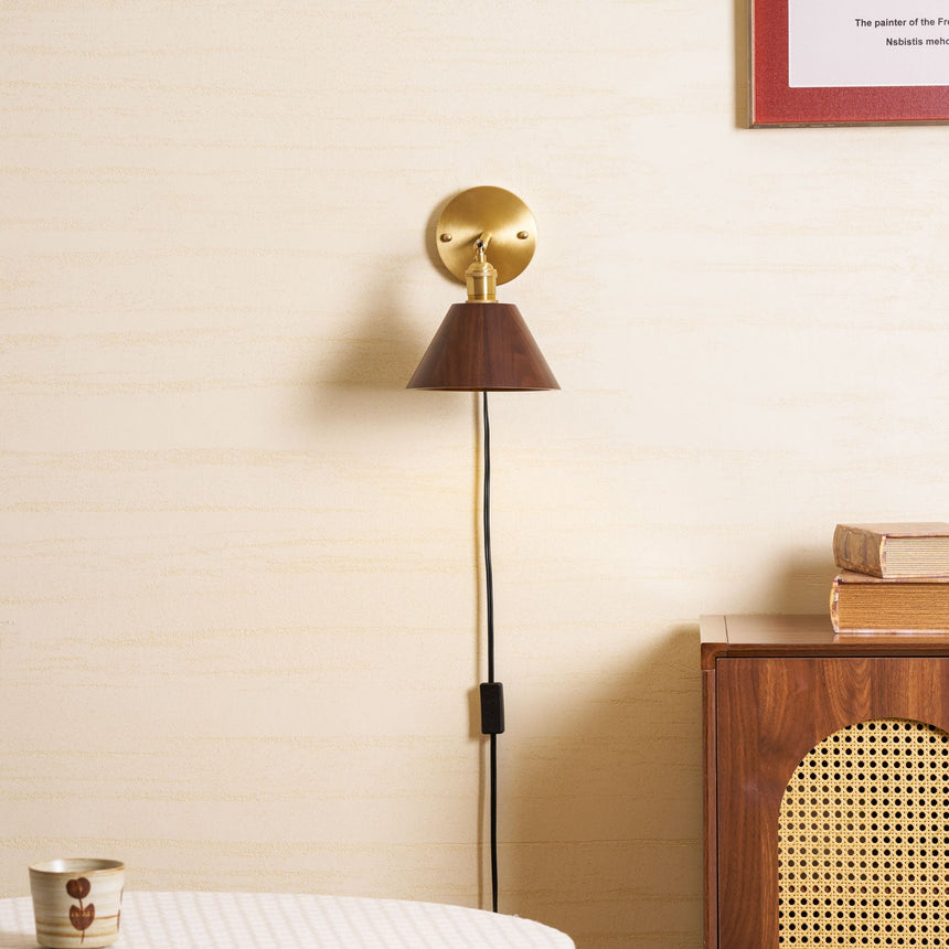 Walnut sconce lit beside a framed print above a caned chair