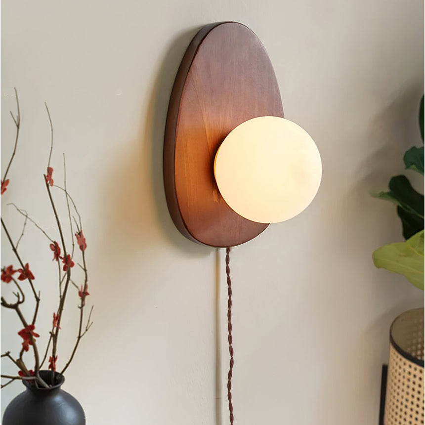 The lit sconce beside a black vase of red budded branches