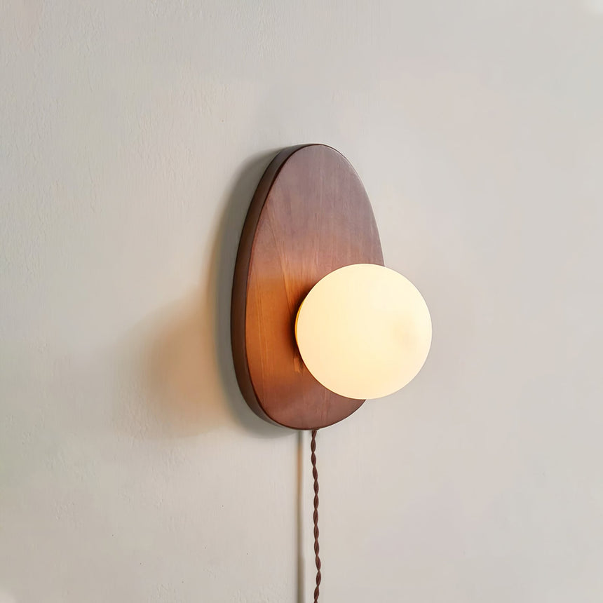 Side view of the walnut plate and the sphere against a plain wall