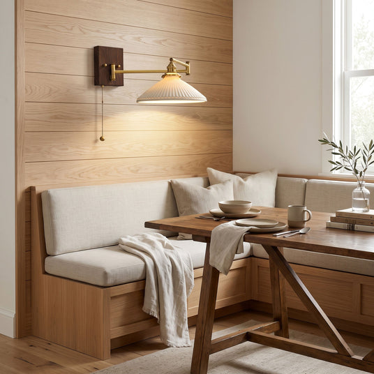 Ceramic wall lamp lit over a bench seat and table in a breakfast nook
