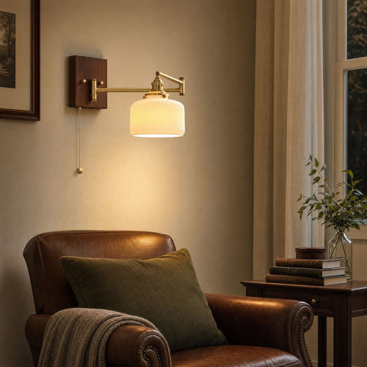 Ceramic wall lamp lit beside a leather armchair in a reading corner