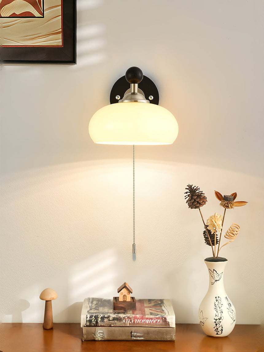 Lamp lit above a wood desk with magazines, a vase and small ornaments