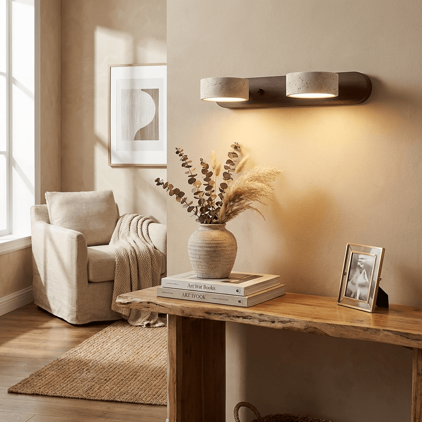 Lit on a warm wall above a console with a tall vase of dried stems and books