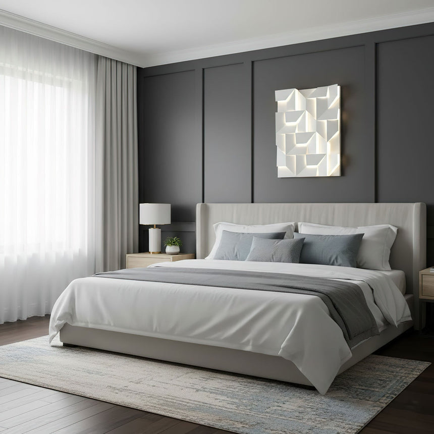 Lit above a bed with a gray headboard, a nightstand and a table lamp beside it