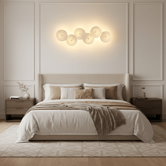 A horizontal row of glowing ceramic discs above an upholstered bed and two nightstands