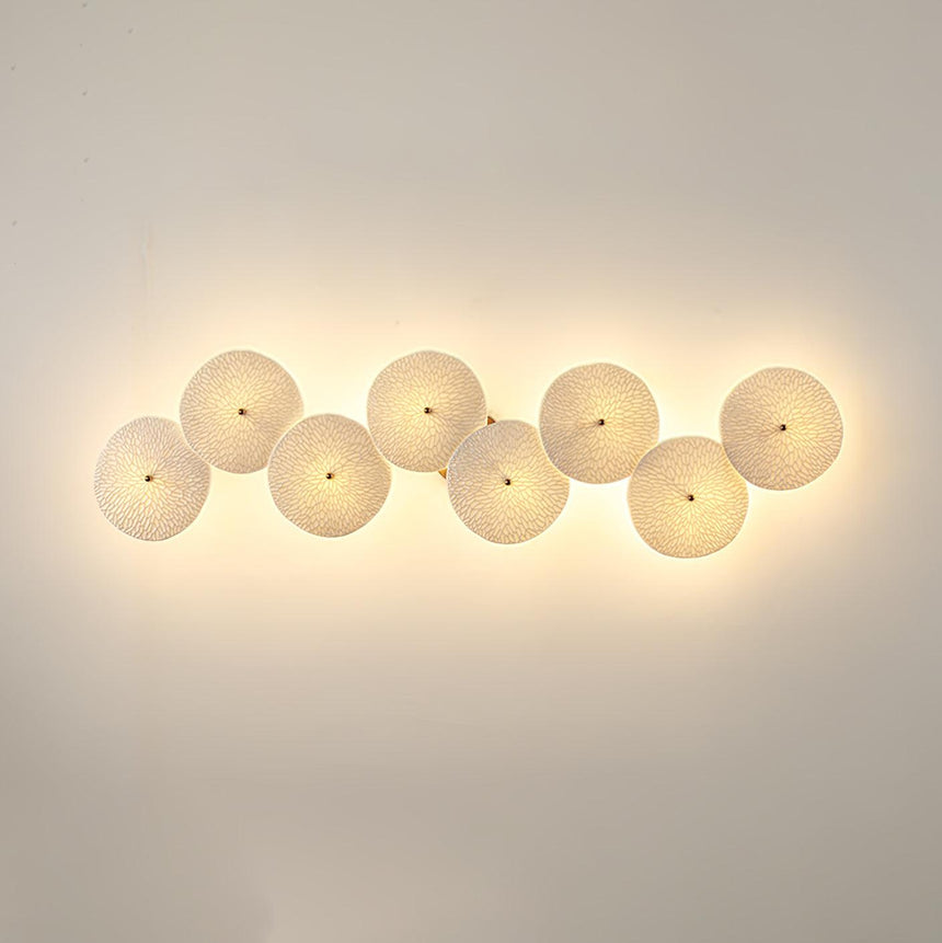 Eight discs in a horizontal row, each glowing warm on a beige wall