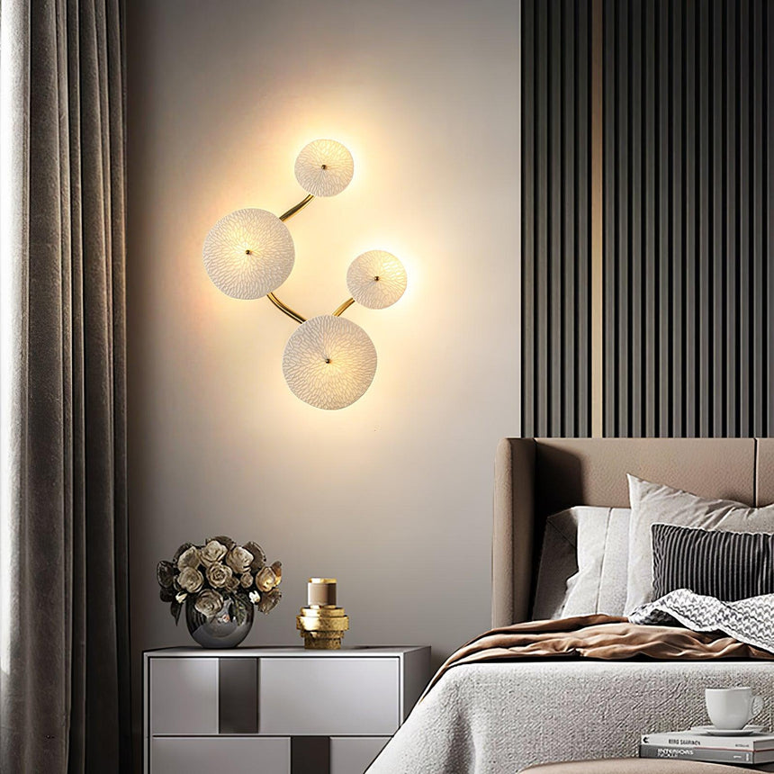 A vertical cluster of discs lit beside a bed and a sideboard